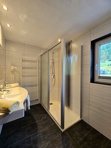 Spacious bathroom with double washbasin, hairdryer, large shower cubicle and window with a beautiful view