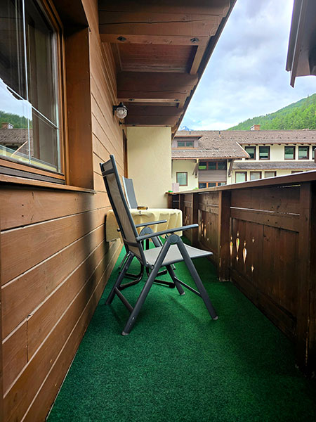 View of the mountain world of Sölden from the balcony with simple chairs and a table