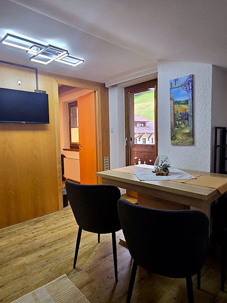 Kitchen dining area with TV on the wall and view of the balcony door